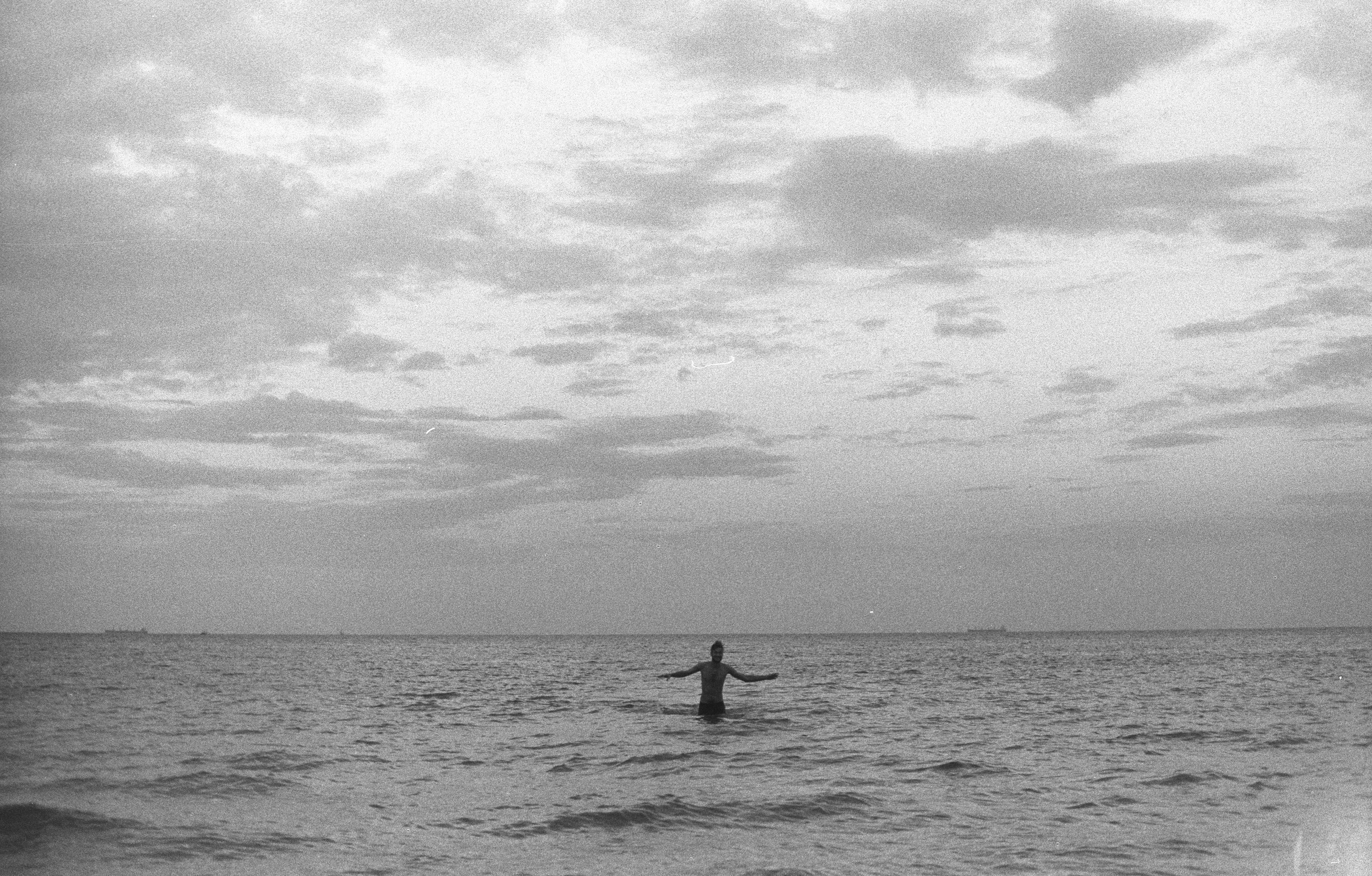 person surfing on sea under cloudy sky during daytime